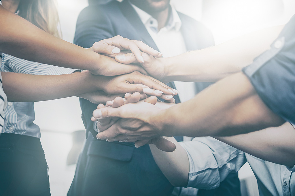 Close up view of young business people putting their hands together. Stack of hands. Unity and teamwork concept.