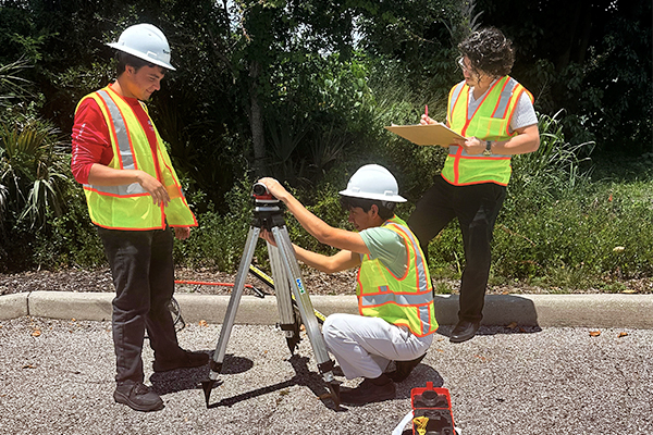 Bowman summer interns in safety vests inspecting equipment.